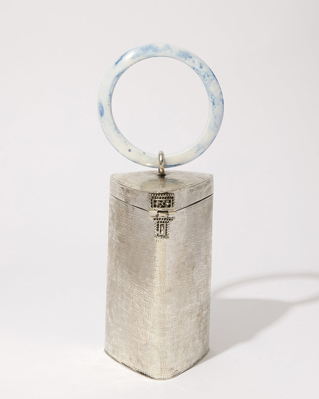 Front view of the handcrafted brass Right Off The Edge bag, highlighting the artisan-made texture and the signature metal clasp