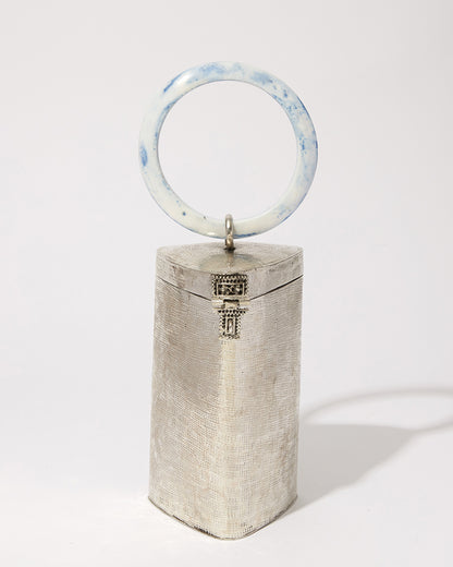 Front view of the handcrafted brass Right Off The Edge bag, highlighting the artisan-made texture and the signature metal clasp