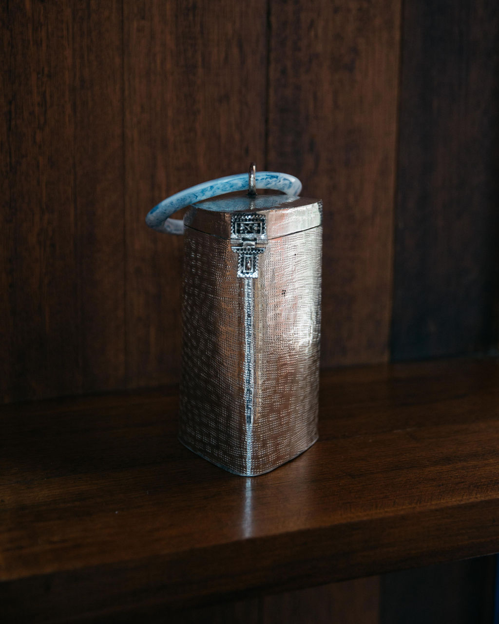 The Right Off The Edge brass bag displayed on a dark wooden shelf, showcasing its function as a sculptural home ornament.