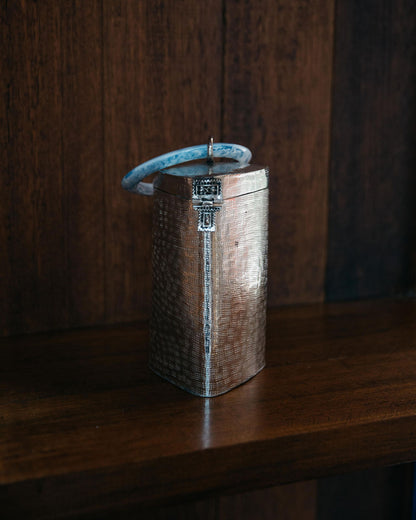 The Right Off The Edge brass bag displayed on a dark wooden shelf, showcasing its function as a sculptural home ornament.