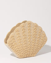 Three-quarter studio view of the Stand Still champagne beaded clutch featuring a sculptural shell-shaped silhouette and embossed beadwork.