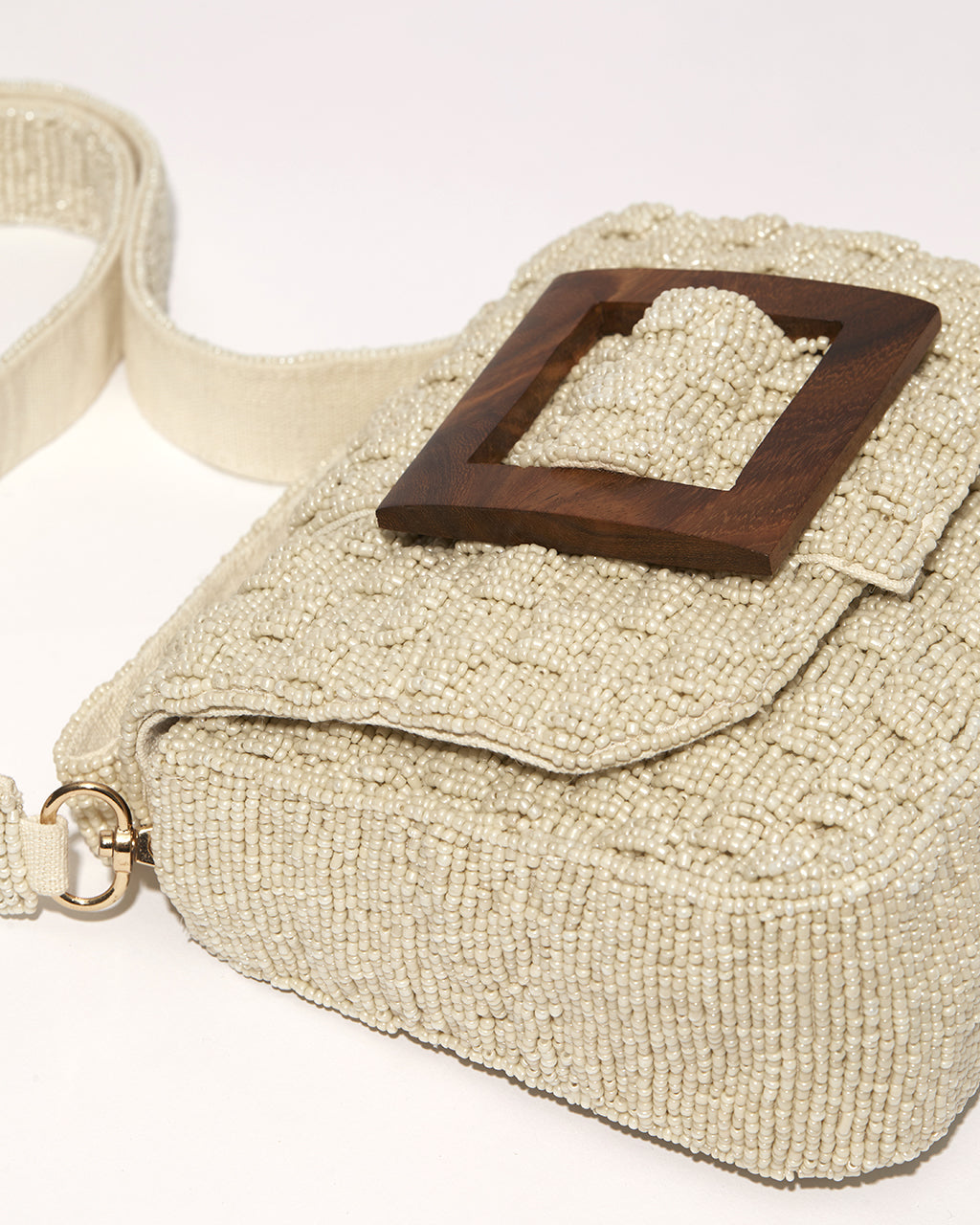 Side view of the white beaded bag highlighting the matching detachable beaded crossbody strap and the depth of the woven construction.